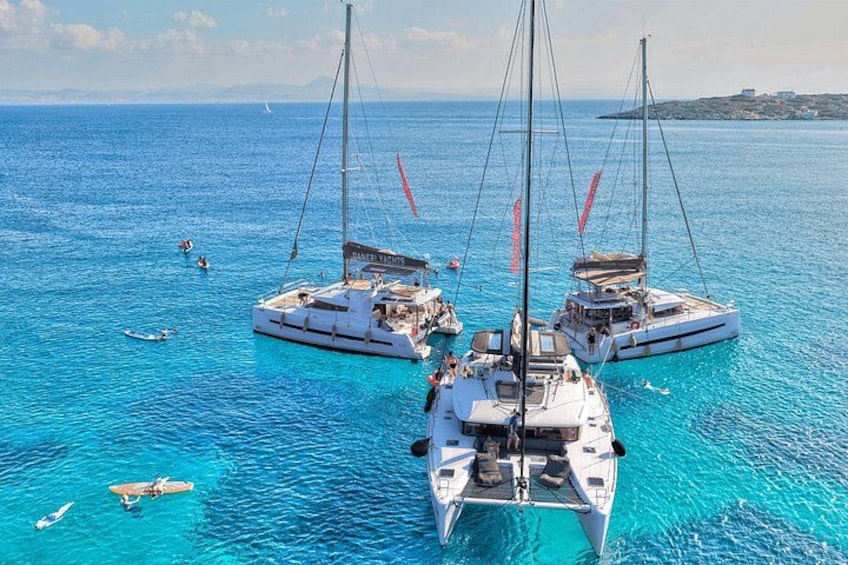 Three sailboats anchored in clear blue waters with a distant island in the background. 4
