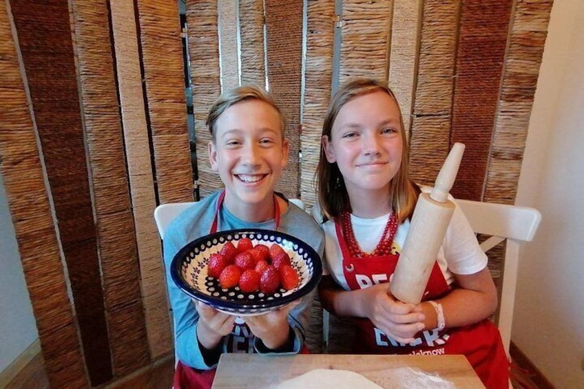 Two people holding a bowl of strawberries and a rolling pin. 4