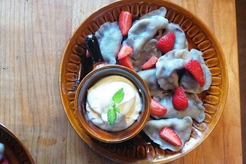 A plate of dumplings with strawberries and a small bowl of yogurt with mint. 2