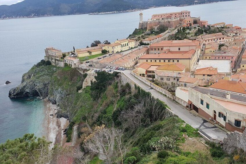 A coastal town with historic buildings, a fortified structure, and a beach. 3