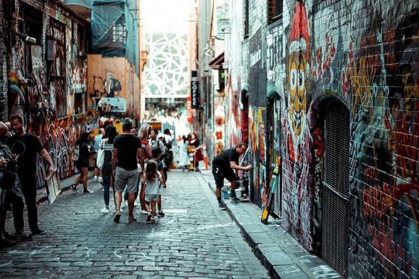 Un callejón estrecho con paredes cubiertas de grafitis, adoquinado y con gente caminando. 2