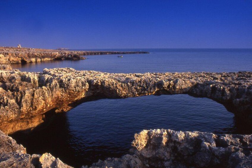 A rocky coastal landscape with a natural arch formation over a body of water. 4