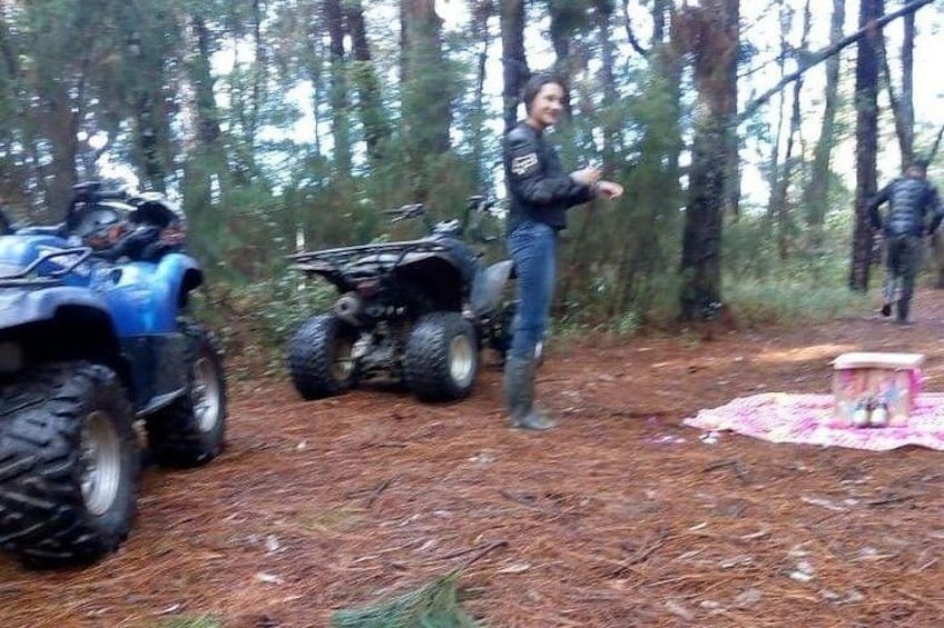 A forest with two ATVs, a blanket, and a small table. 5