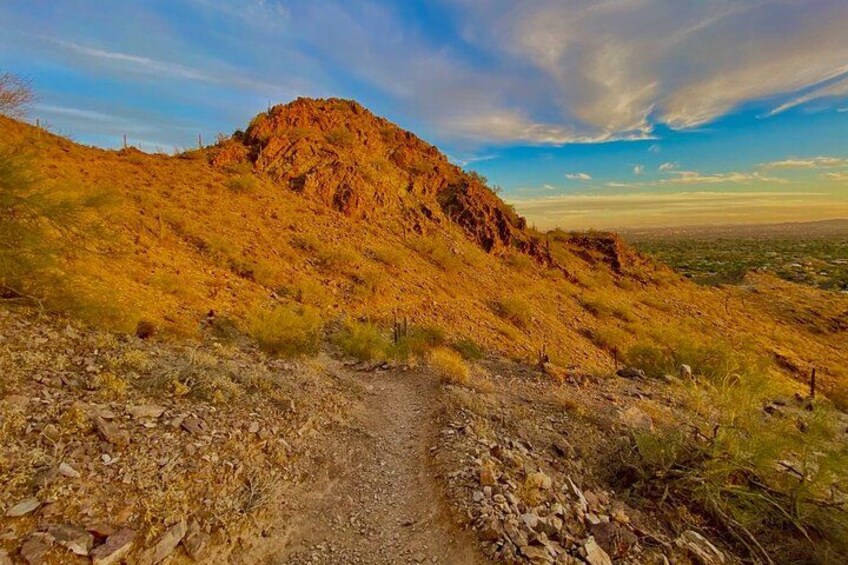 A dirt path leading up a rocky hill with sparse vegetation. 1