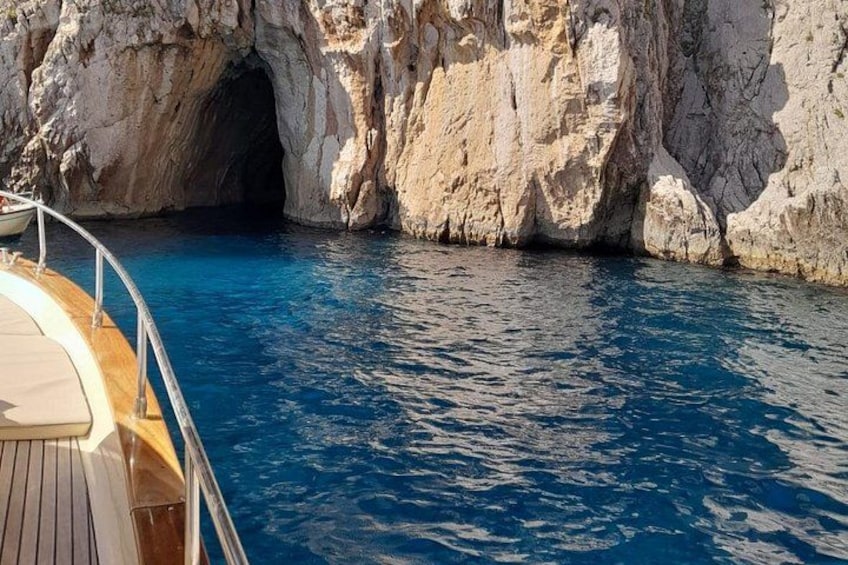 A boat near a rocky cave entrance with clear blue water. 2