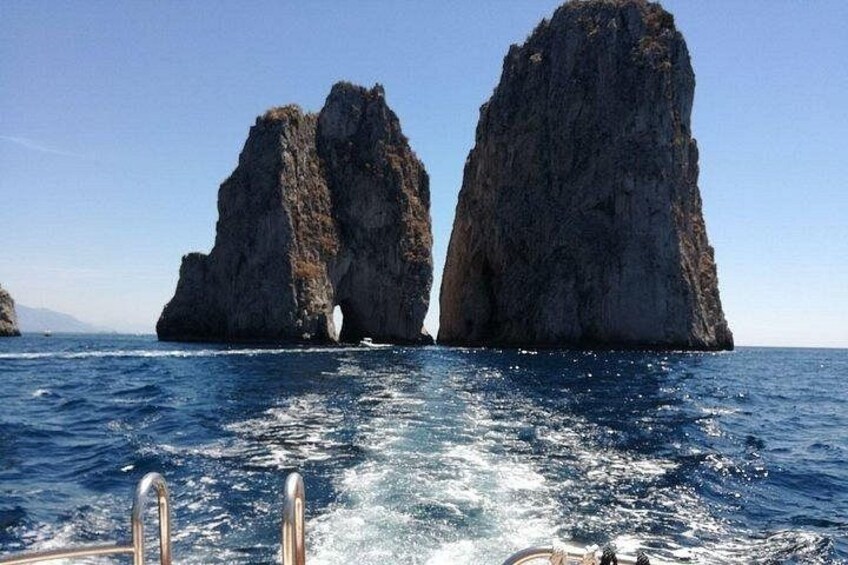 A boat in the ocean with two large rock formations in the background. 5