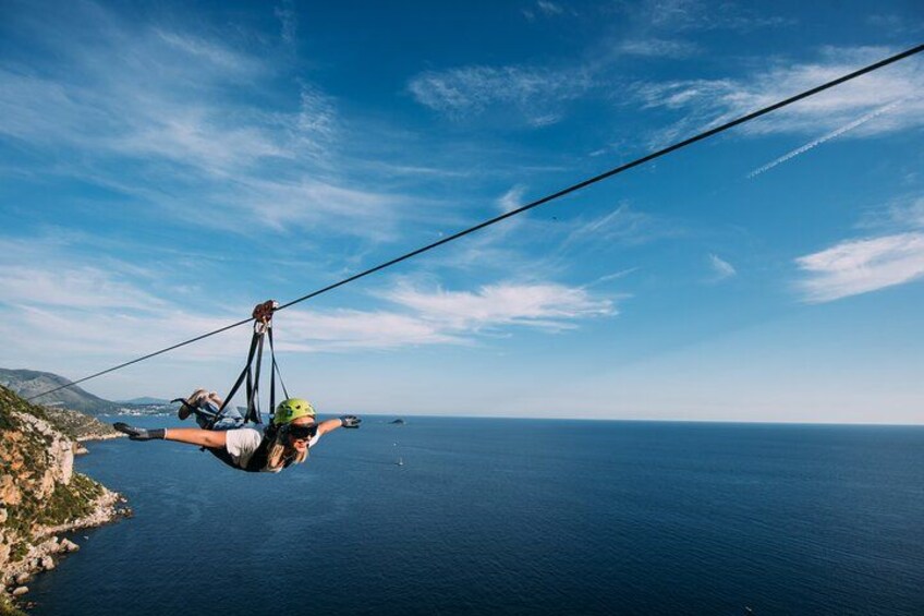 Eine Person macht Bungeesprung über einer Küstenregion bei blauem Himmel und ruhiger See. 1