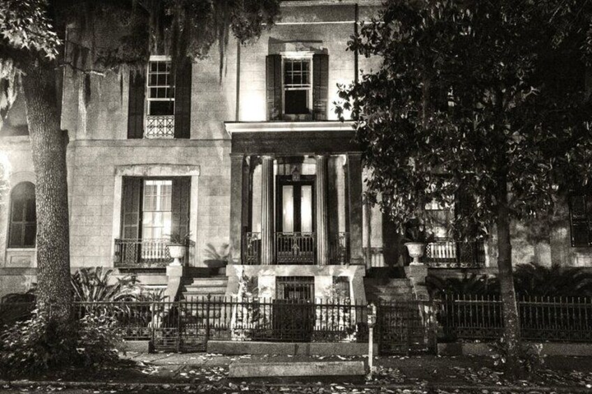 A historic building with a large tree in front, a gated entrance, and a well-maintained lawn. 3