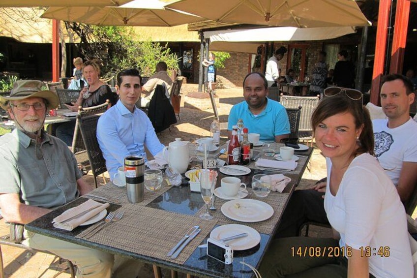 A group of people dining outdoors at a table with various dishes and drinks. 2