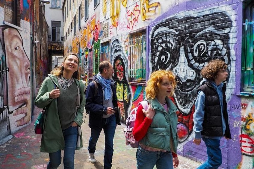 Een smalle steeg met kleurrijke graffiti, waaronder een groot schedel- en gezichtsmural. 5