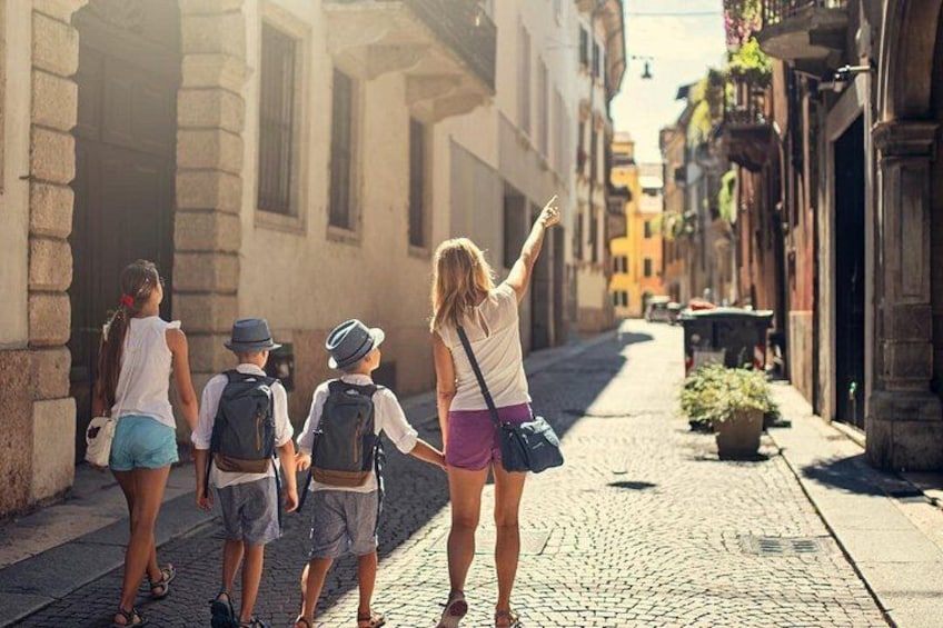 A group of people walking down a cobblestone street in a historic town. 2