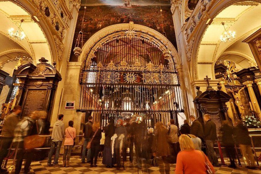 Interior de iglesia ornamentado con un gran portón decorativo y gente reunida alrededor. 2