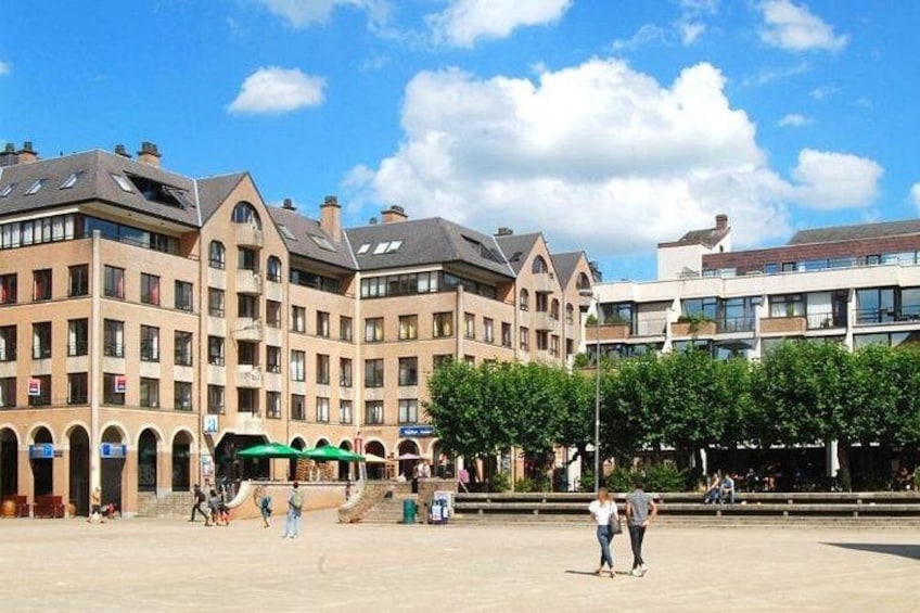 A public square with buildings, trees, and people. 1