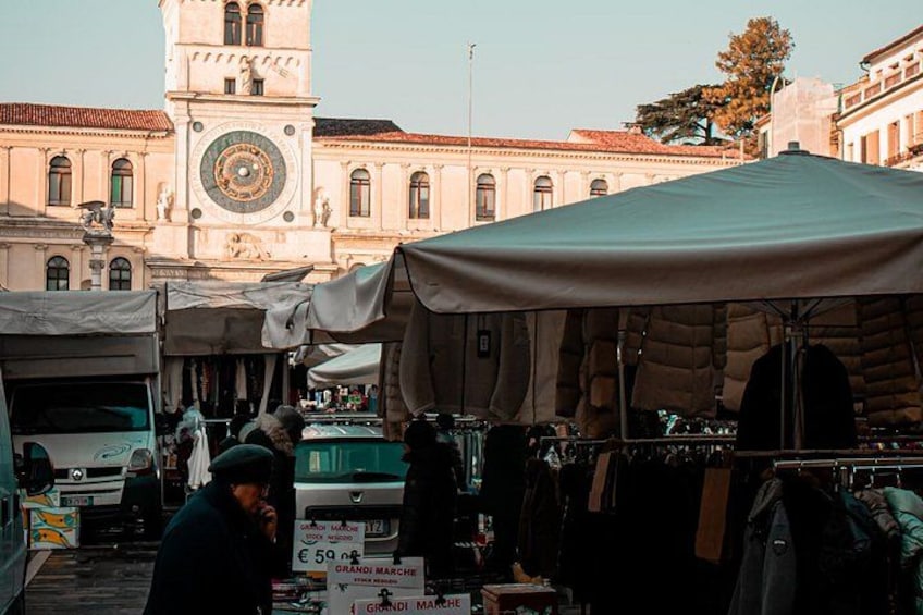 Un mercado con carpas y una torre del reloj al fondo. 4