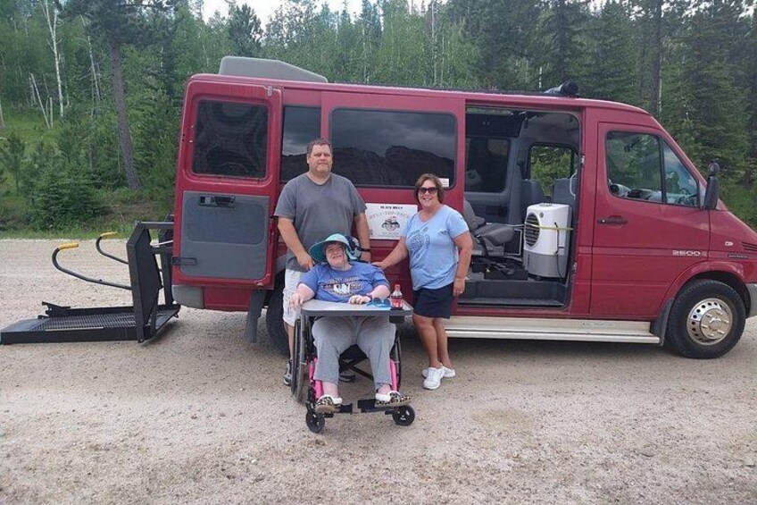 A red van, a wheelchair, and two people standing beside it. 2