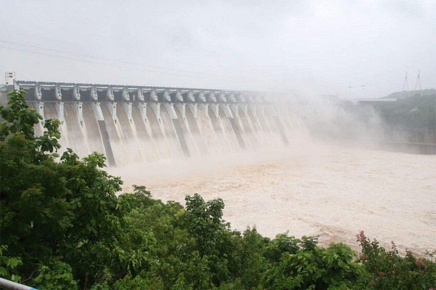 A dam releasing water, with a forested area in the foreground. 2