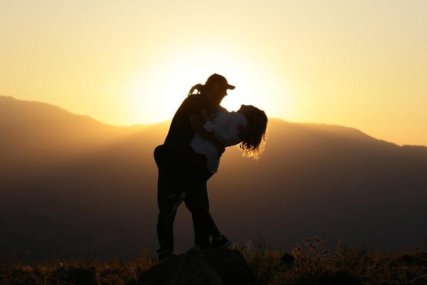 A couple embracing on a mountain peak during sunset. 1