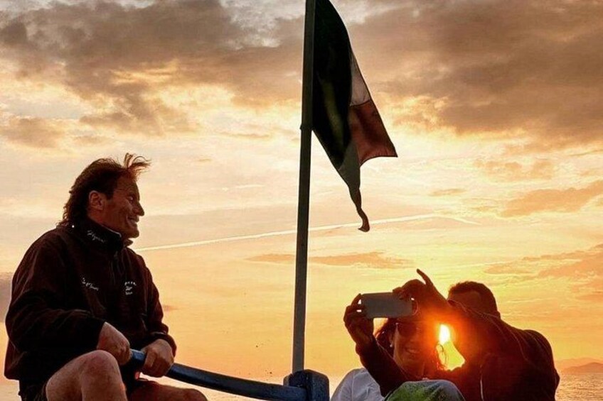 A sunset with a flag, a person holding a camera, and another person taking a photo. 1