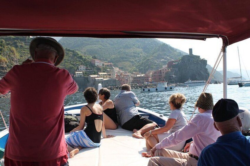 A group of people on a boat, a coastal town, and a mountainous landscape in the background. 2