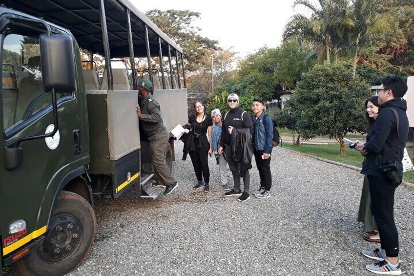 A group of people standing around a green military-style vehicle with a covered cargo area. 3