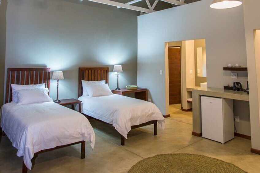 A hotel room with two beds, bedside tables, a desk, a refrigerator, and a mirror. 2