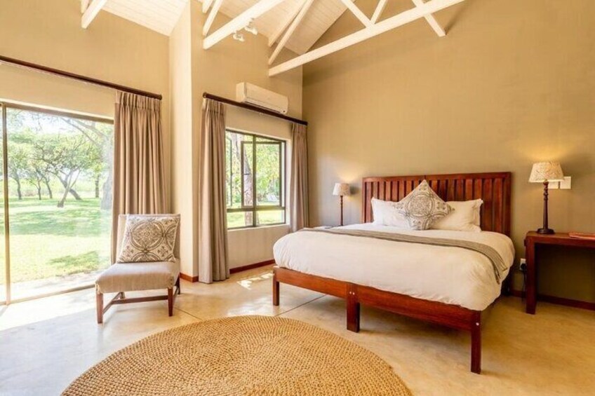A bedroom with a large bed, a chair, and a view of a garden. 5