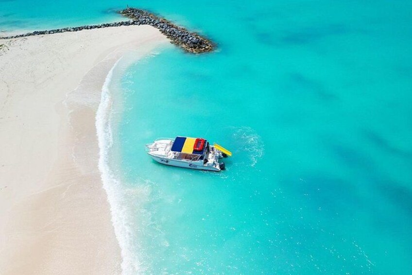 Un bote con un toldo colorido sobre aguas turquesas cerca de una playa arenosa. 2