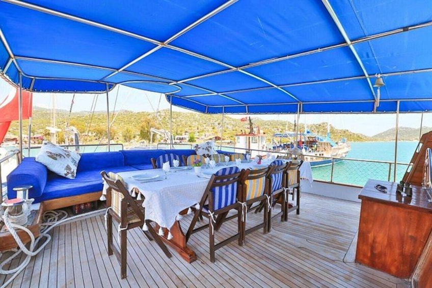 A covered deck with a table and chairs, overlooking a body of water with boats. 2