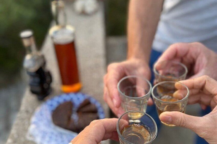 Een persoon houdt een shotglas met een drankje vast, samen met een fles en een chocoladereep op een tafel. 4