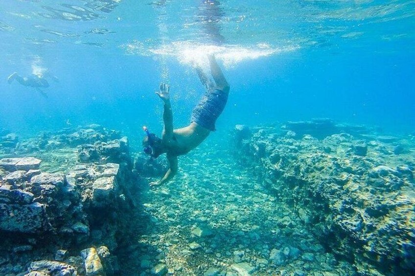 A person swimming underwater near a rocky seabed. 2