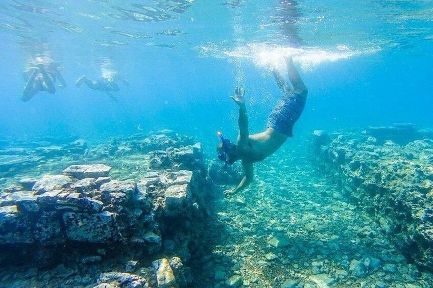 A person swimming underwater near a rocky seabed. 1