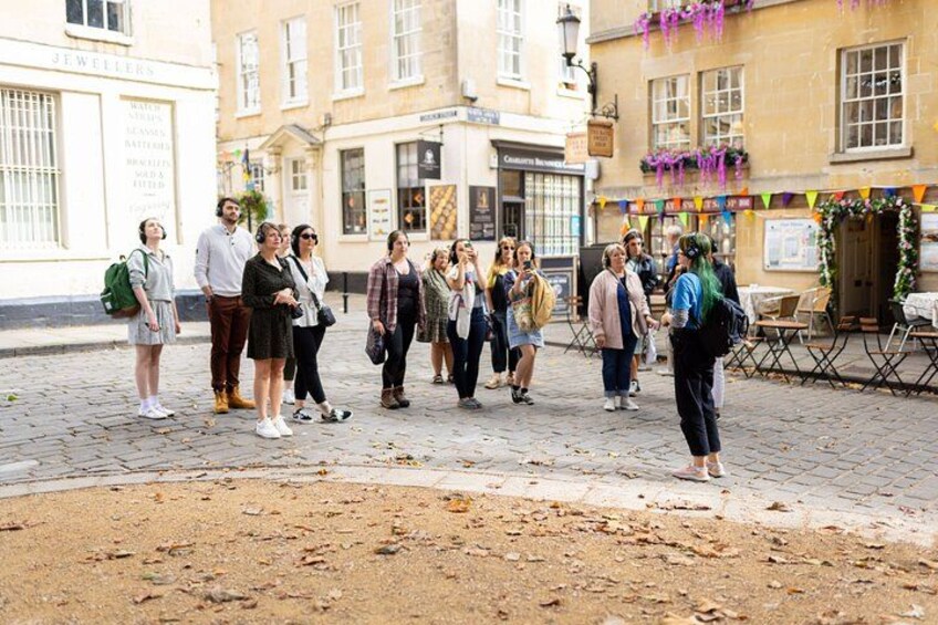 A group of people standing on a cobblestone street with buildings in the background. 2