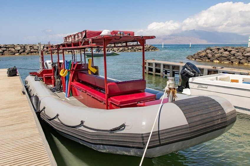 Een motorboot aan een steiger, met een rotsachtige kustlijn op de achtergrond. 4