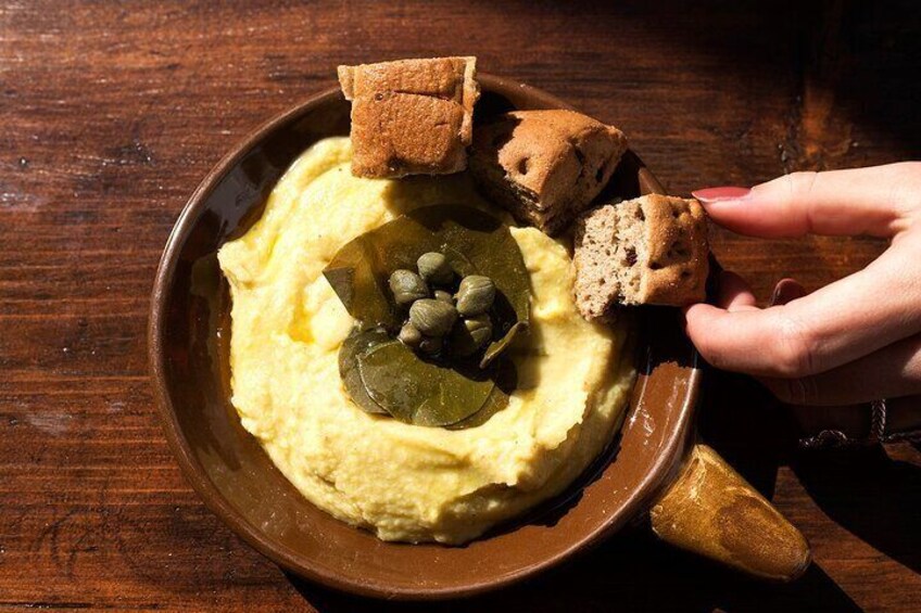 A bowl of mashed potatoes topped with capers and bread pieces. 4