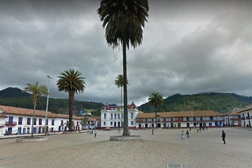 A plaza with buildings, palm trees, and a cloudy sky. 5