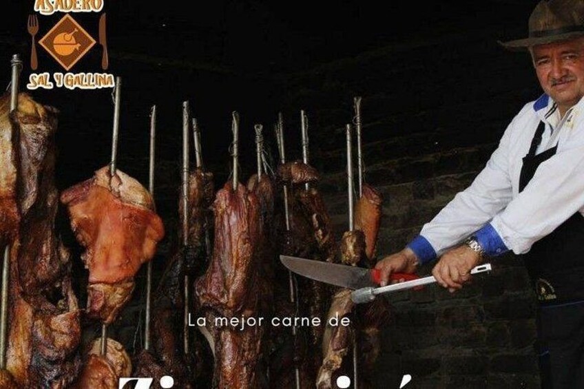 A person carving meat on a spit over an open flame. 2
