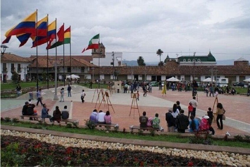 A plaza with flags, a building with a green roof, and people sitting and walking. 4