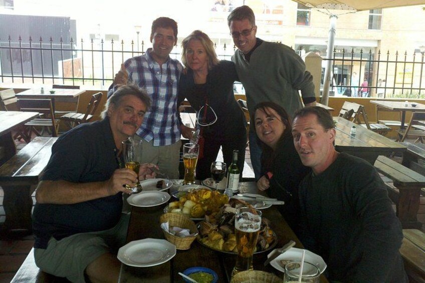 A group of people sitting around a table with food and drinks. 3