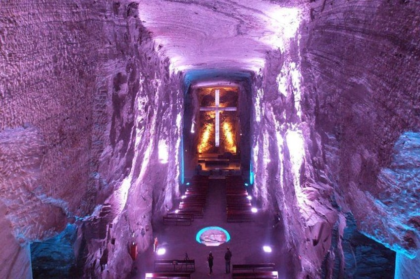 A tunnel with a cross at the end, illuminated by purple and blue lights. 1