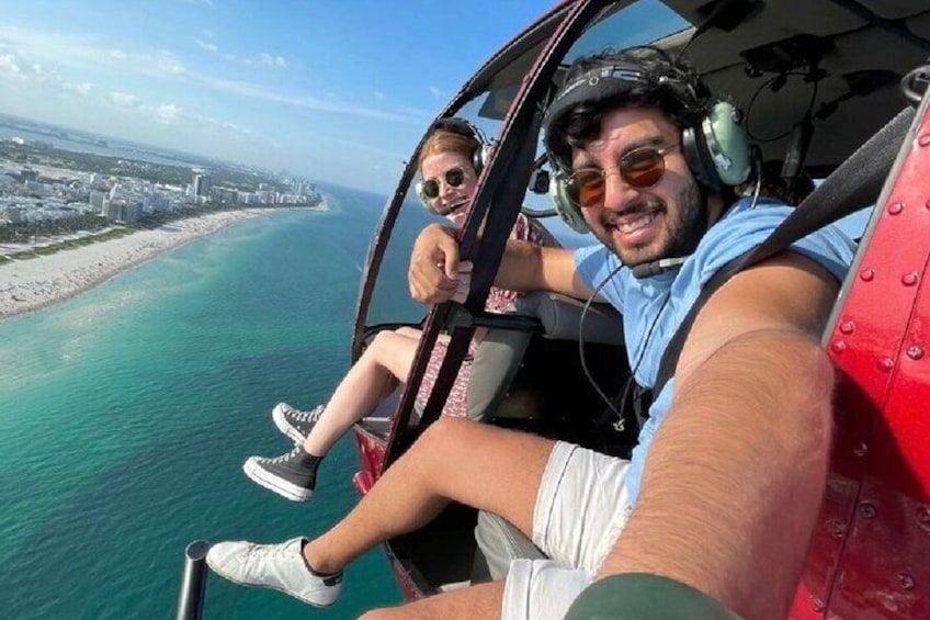 En helikopter flyger över ett kustområde med en strand och hav. 2