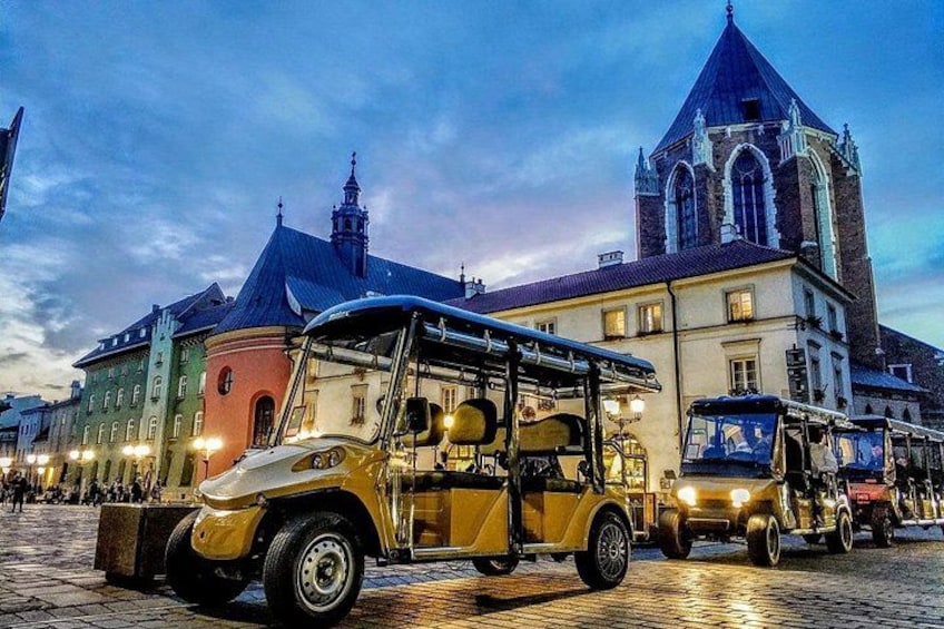 A vintage jeep in front of a historic building with a tower. 1