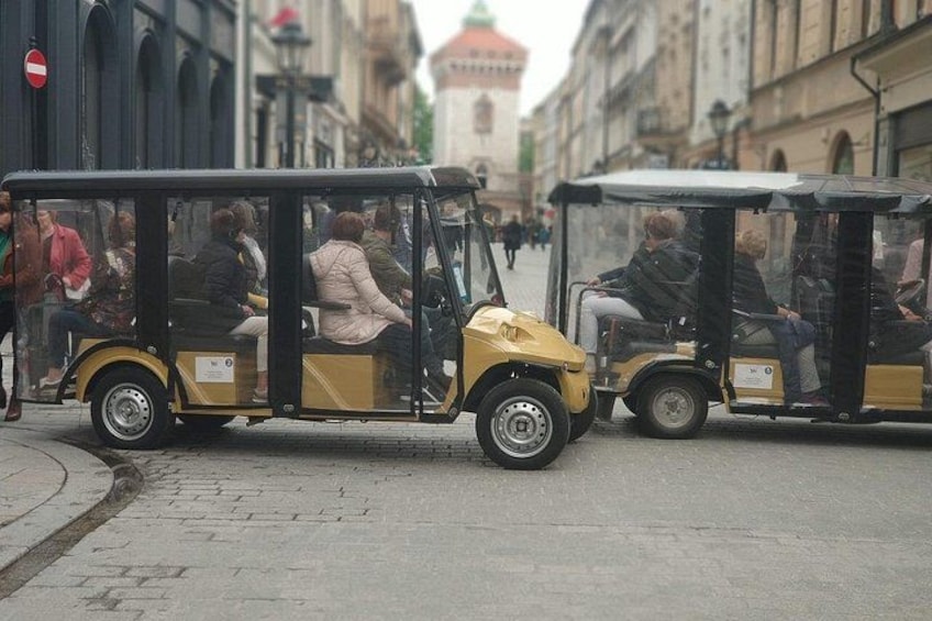 A yellow tram with passengers, a no entry sign, and historic buildings in the background. 5