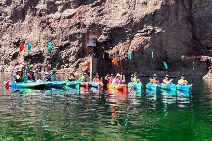 Des personnes se trouvent dans des bateaux aux couleurs vives, naviguant sur une rivière paisible, avec des falaises rocheuses en arrière-plan. 5
