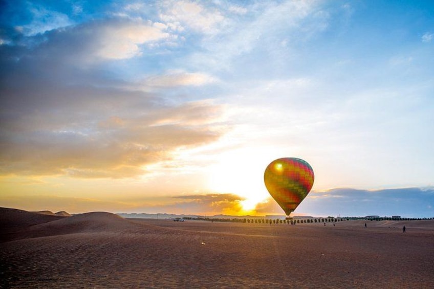 Eine Heißluftballonfahrt über einer Wüstenlandschaft, im Hintergrund ein Sonnenuntergang. 5