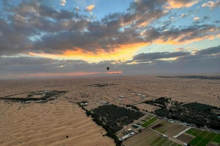 Weite Wüstenlandschaft mit vereinzelten grünen Feldern und einem Heißluftballon in der Ferne. 4