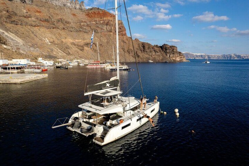 A sailboat docked at a marina with rocky cliffs in the background. 4