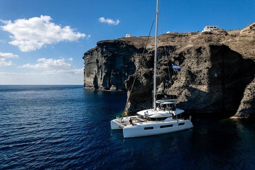 A sailboat anchored near a rocky coastline with cliffs. 1
