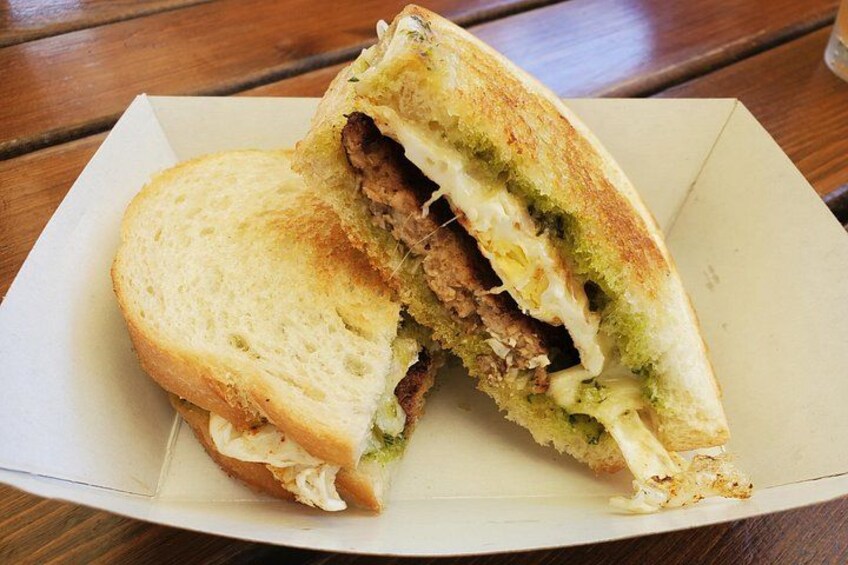 A sandwich cut in half, placed on a white paper plate on a wooden table. 4