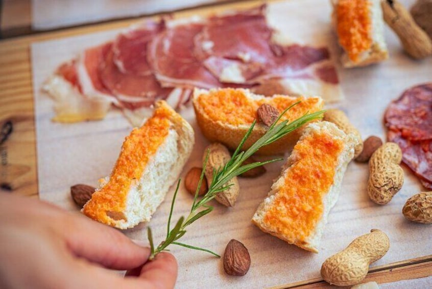A wooden board with bread, almonds, and a sprig of rosemary. 3