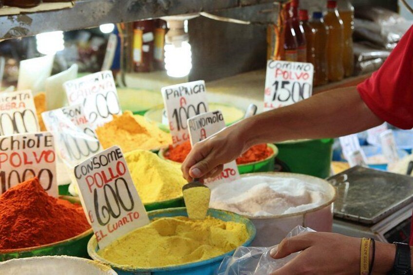 A person scooping yellow powder labeled 'Consome Pollo' from a bowl. 3